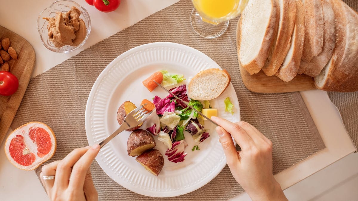 Top view of a nutritious breakfast setup with salad, bread, and fresh juice, perfect for a healthy start.